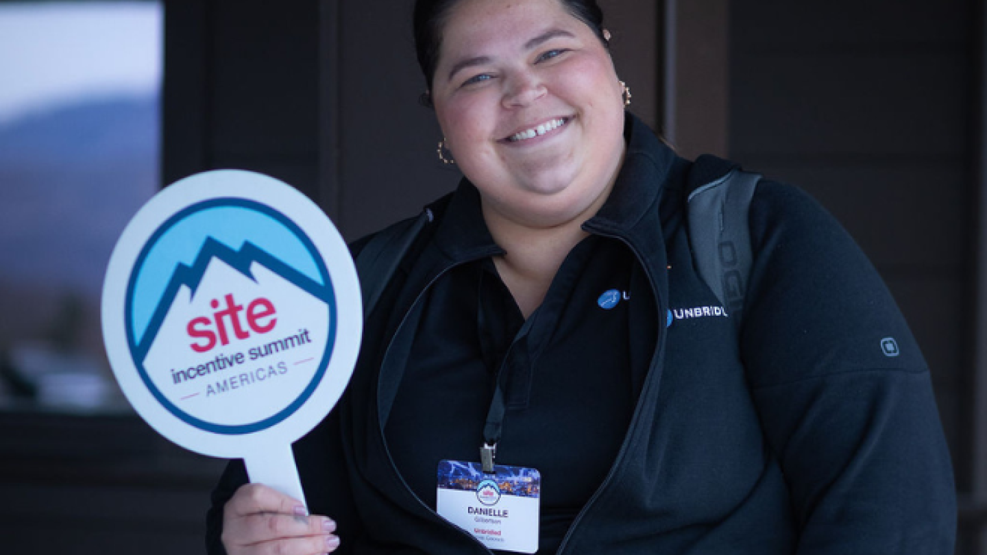 A woman holds up a paddle sign with the event name and logo