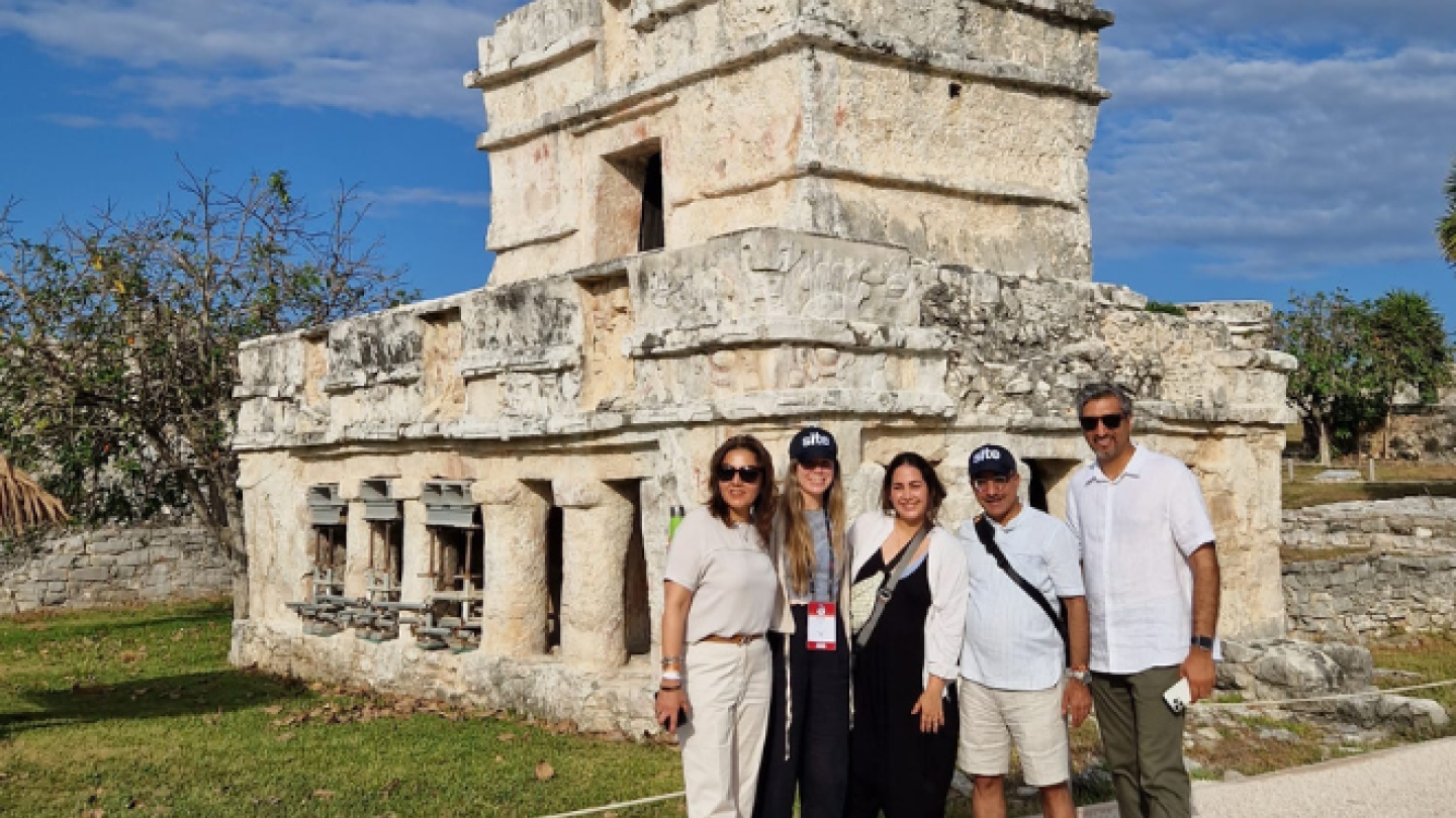 a handful of group members pose in front of a ruin site 