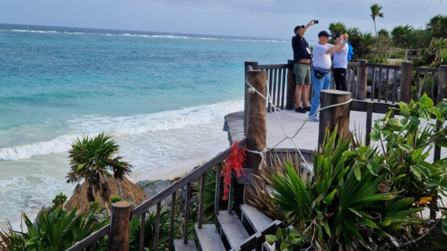beach and ruins, with small group taking selfies on the right of the image